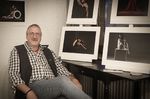 Links im Bild sitzend Uli Berger, rechts davon einige seiner Nude-Art Fotographien